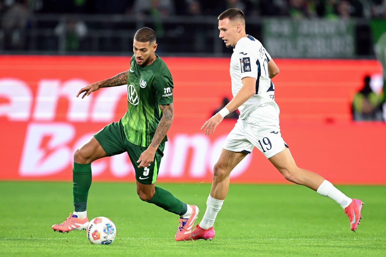 Vinicius Souza, do VfL Wolfsburg, disputa a posse de bola com Tim Lemperle, do TSG 1899 Hoffenheim, durante a partida da Bundesliga entre VfL Wolfsburg e TSG Hoffenheim, na Volkswagen Arena, em 2 de novembro de 2025, em Wolfsburg, Alemanha.