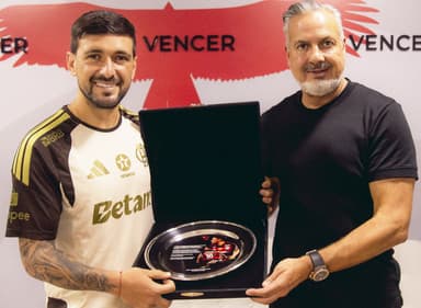 Arrascaeta e José Boto sorriem com placa em homenagem aos 100 gols de Arrascaeta