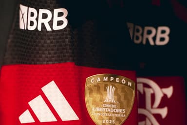 Close no uniforme 1 do Flamengo com logo do BRB, escudo, patch de campeão da Libertadores e símbolo da Adidas