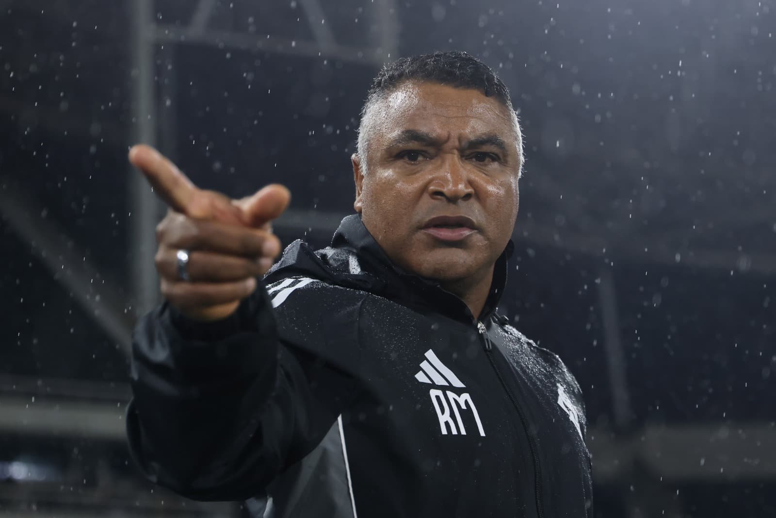 Roger Machado aponta para a direita com o rosto franzido