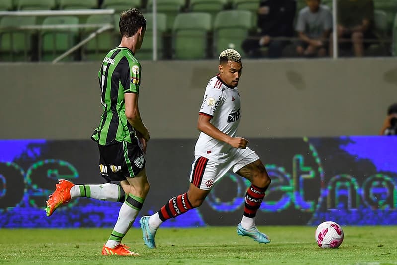 Matheuzinho, atleta do Flamengo conduzindo a bola, enquanto jogador adversário se aproxima