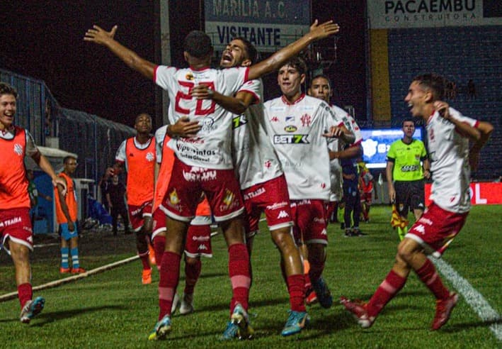 Com a camisa 20, Lucas Rabello abre os braços e comemora o gol com seus companheiros no Bangu