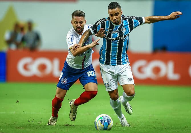 Everton Ribeiro disputa bola com Fábio em Bahia x Grêmio; adversário do Flamengo, time gaúcho perdeu 2 jogos fora de casa no Brasileirão