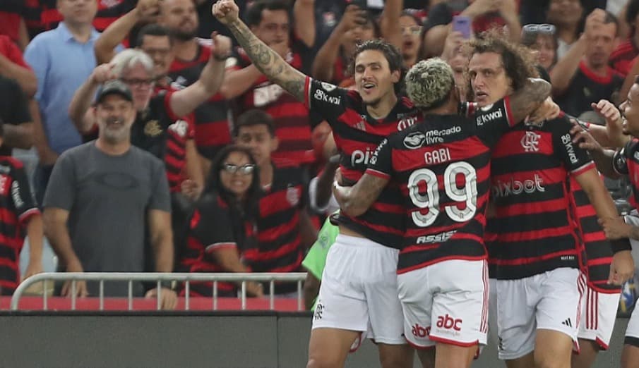 David Luiz é abraçado pelo time com torcida vibrando ao fundo na comemoração do gol da vitória do flamengo diante do Bahia