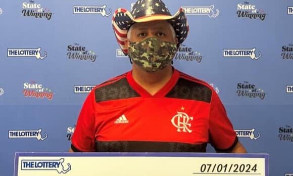 Frederico Sampaio com camisa do Flamengo enquanto recebe prêmio da loteria