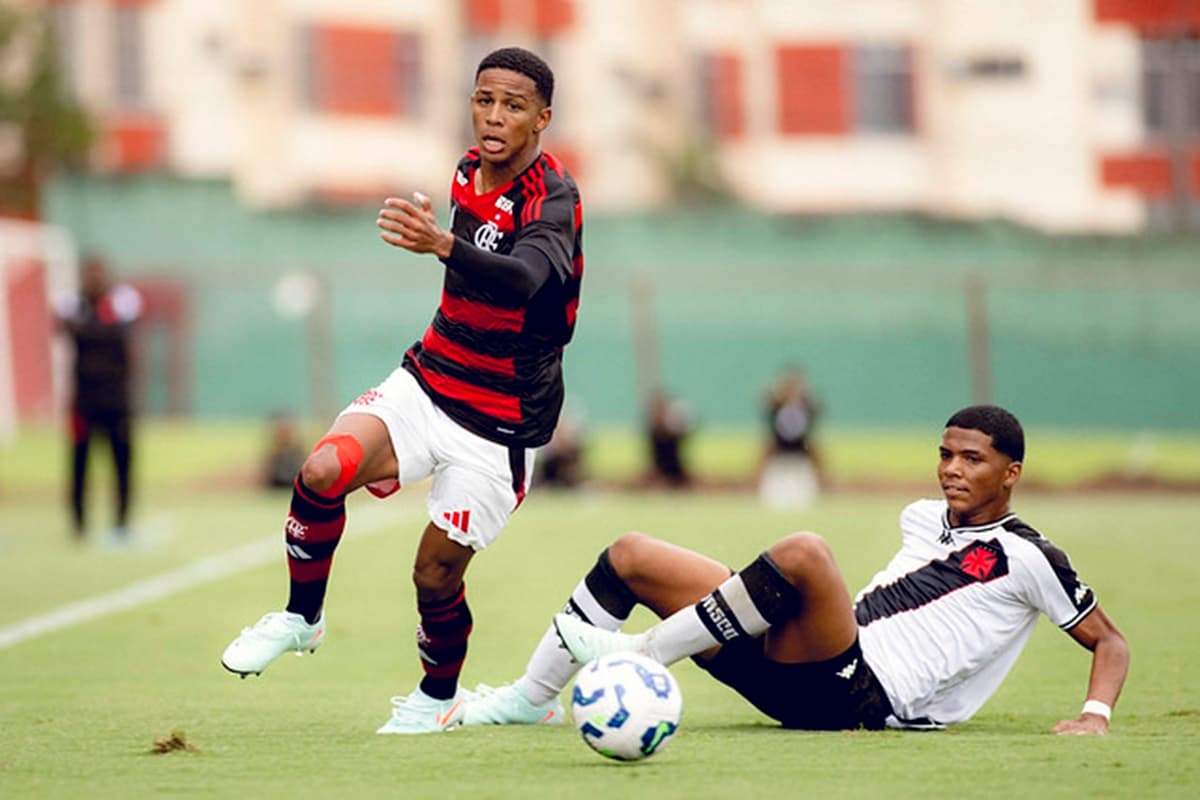 Jogador do Flamengo tenta jogada e é observado por atleta do Vasco