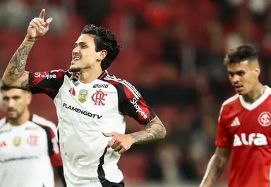 Com o Manto branco, Pedro comemora segundo gol sobre o Internacional no Beira-Rio apontando o dedo direito para o céu; ao fundo, Richard, do Internacional, observa com semblante de irritação