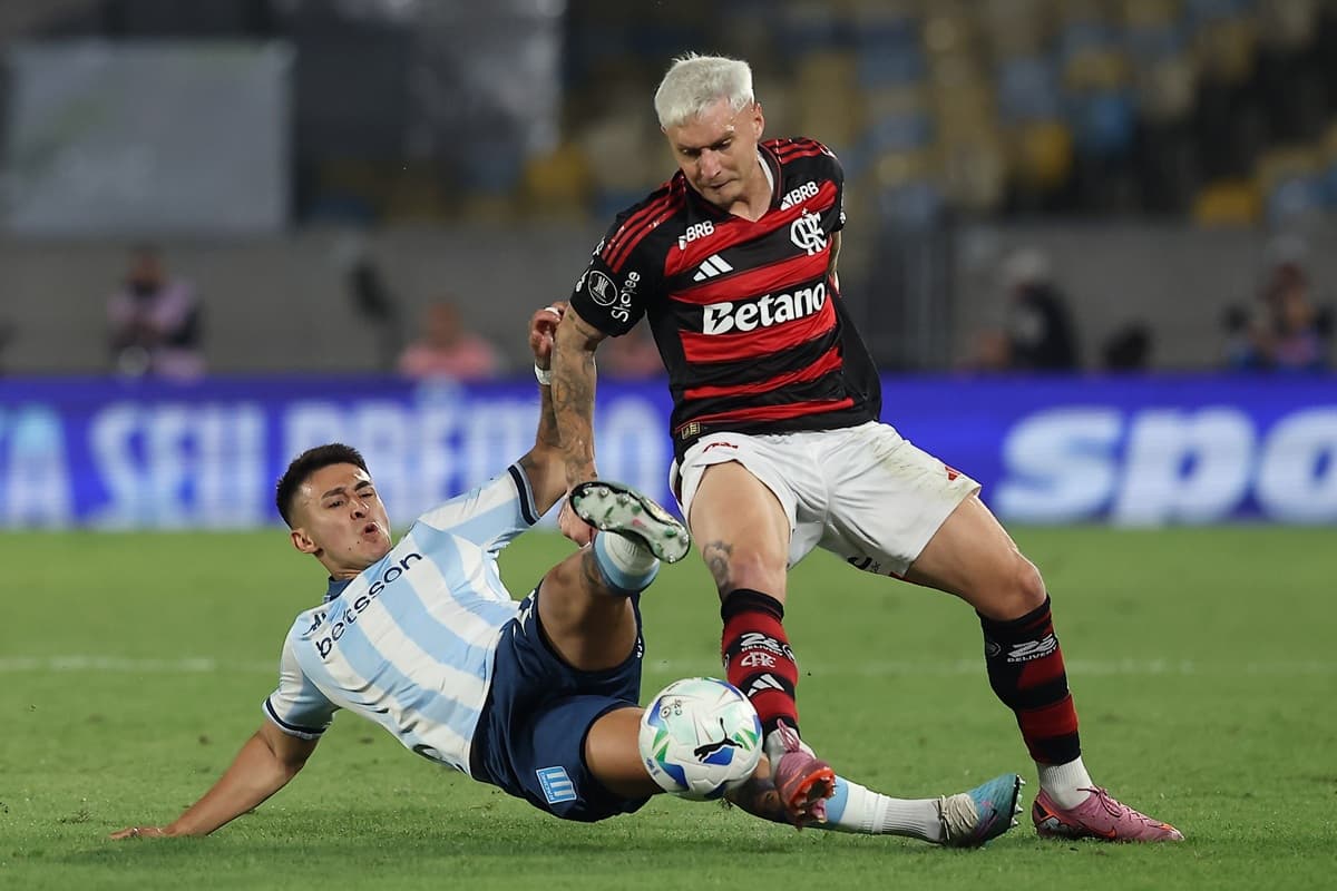 Jogador do Racing dá carrinho para disputar bola com Varela, lateral do Flamengo, em jogo entre as duas equipes no Maracanã