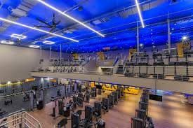 Interior de uma academia da Smart Fit com equipamentos de musculação e iluminação azul.