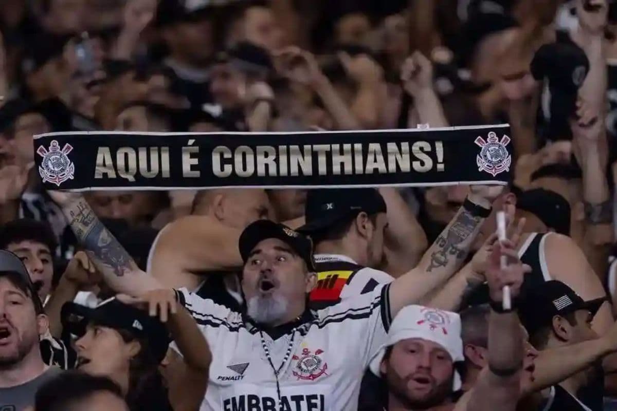 Torcedor do Corinthians segura uma faixa escrito Aqui é Corinthians!