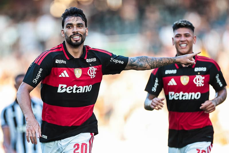 Lucas Paquetá aponta para o lado ao comemorar gol pelo Flamengo, contra o Botafogo, no Campeonato Carioca, com Jorge Carrascal sorrindo ao fundo