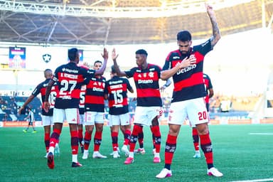 Paquetá comemora gol apontando o dedo para o céu; ao fundo, jogadores se cumprimentam