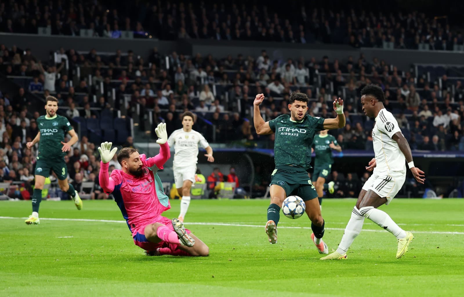Vinicius Junior, do Real Madrid, perde uma chance ao ser disputado por Matheus Nunes e Gianluigi Donnarumma, do Manchester City, durante a partida da 6ª rodada da fase de grupos da Liga dos Campeões da UEFA 2025/26 entre Real Madrid C.F. e Manchester City